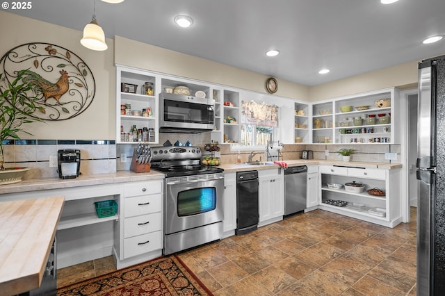 kitchen with stainless steel appliances, a sink, white cabinets, open shelves, and tasteful backsplash