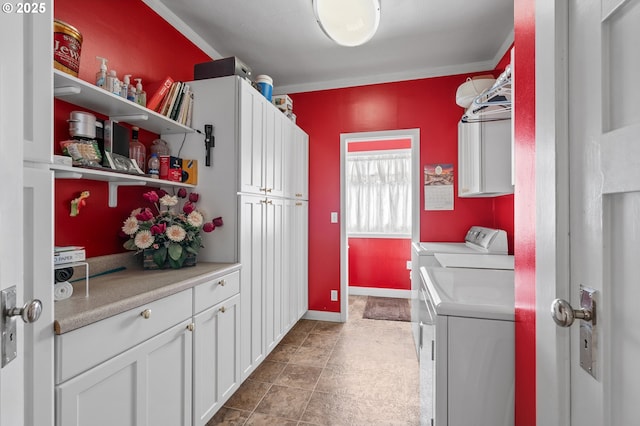 laundry area featuring ornamental molding, washer and clothes dryer, cabinet space, and baseboards