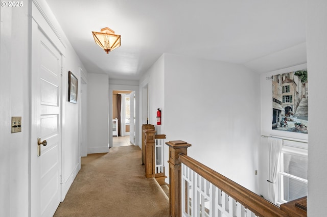 hallway featuring vaulted ceiling, carpet floors, an upstairs landing, and baseboards