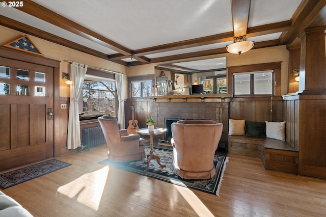 living area with a tiled fireplace, beamed ceiling, coffered ceiling, and wood finished floors