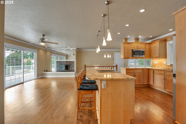 11675 SW Lynn St, Portland, OR 97223 - kitchen with stainless steel microwave, a textured ceiling, a ceiling fan, a glass covered fireplace, and ornamental molding
