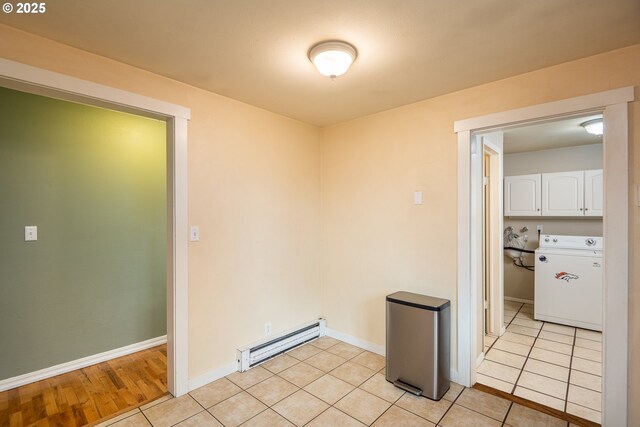 spare room featuring a baseboard radiator, washer / clothes dryer, baseboards, and light tile patterned floors