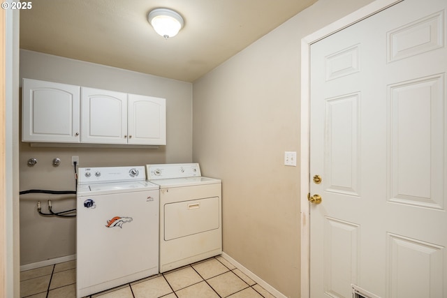 laundry area featuring baseboards, cabinet space, washing machine and clothes dryer, and light tile patterned floors