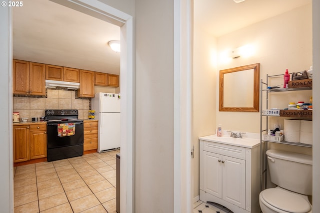 interior space featuring toilet, tasteful backsplash, vanity, and tile patterned floors