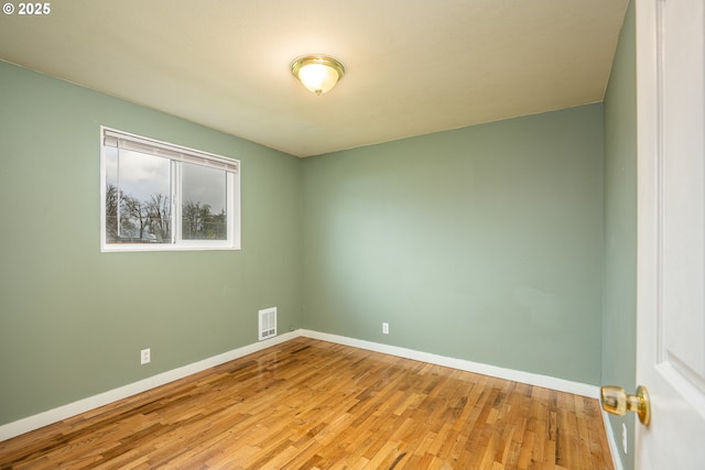 unfurnished room with baseboards, visible vents, and wood finished floors