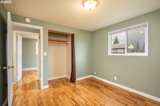 unfurnished bedroom featuring a closet, light wood-style flooring, and baseboards