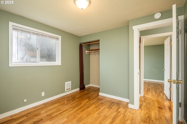 unfurnished bedroom with light wood-style floors, baseboards, visible vents, and a closet