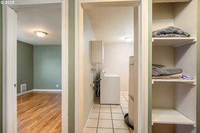 clothes washing area featuring light tile patterned floors, washer / clothes dryer, visible vents, laundry area, and baseboards