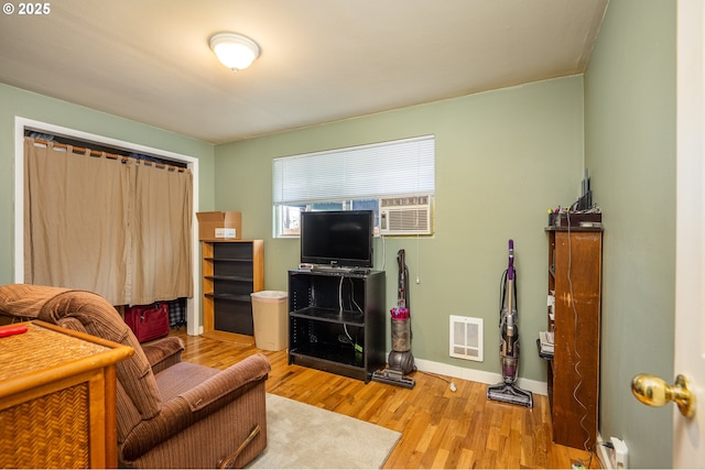 living room with wood finished floors, visible vents, and baseboards