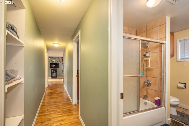 hall featuring baseboards, visible vents, and light wood-style floors