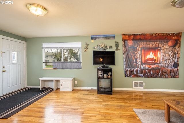 unfurnished living room featuring visible vents, baseboards, and wood finished floors