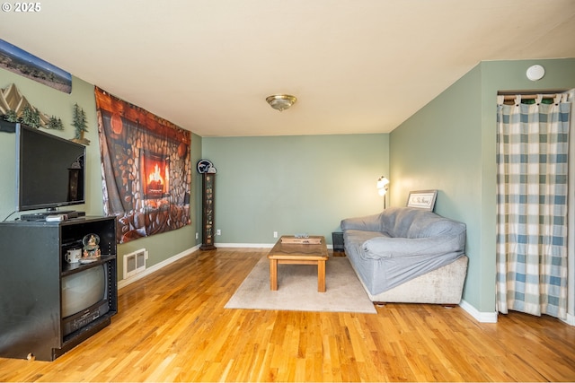 living room featuring visible vents, baseboards, and wood finished floors