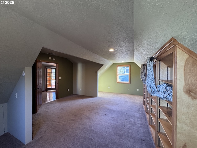 additional living space featuring carpet, lofted ceiling, and a textured ceiling