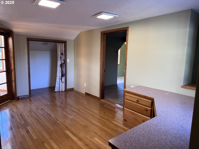 empty room featuring vaulted ceiling, dark hardwood / wood-style floors, and a textured ceiling