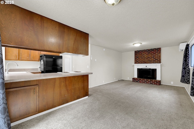unfurnished living room with carpet floors, a fireplace, a textured ceiling, a wall unit AC, and a sink
