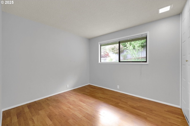 empty room featuring baseboards, a textured ceiling, and wood finished floors