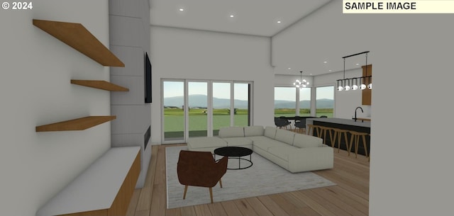 living room featuring a high ceiling, a chandelier, a mountain view, and light hardwood / wood-style flooring