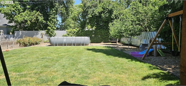 view of yard featuring a fenced in pool and a playground