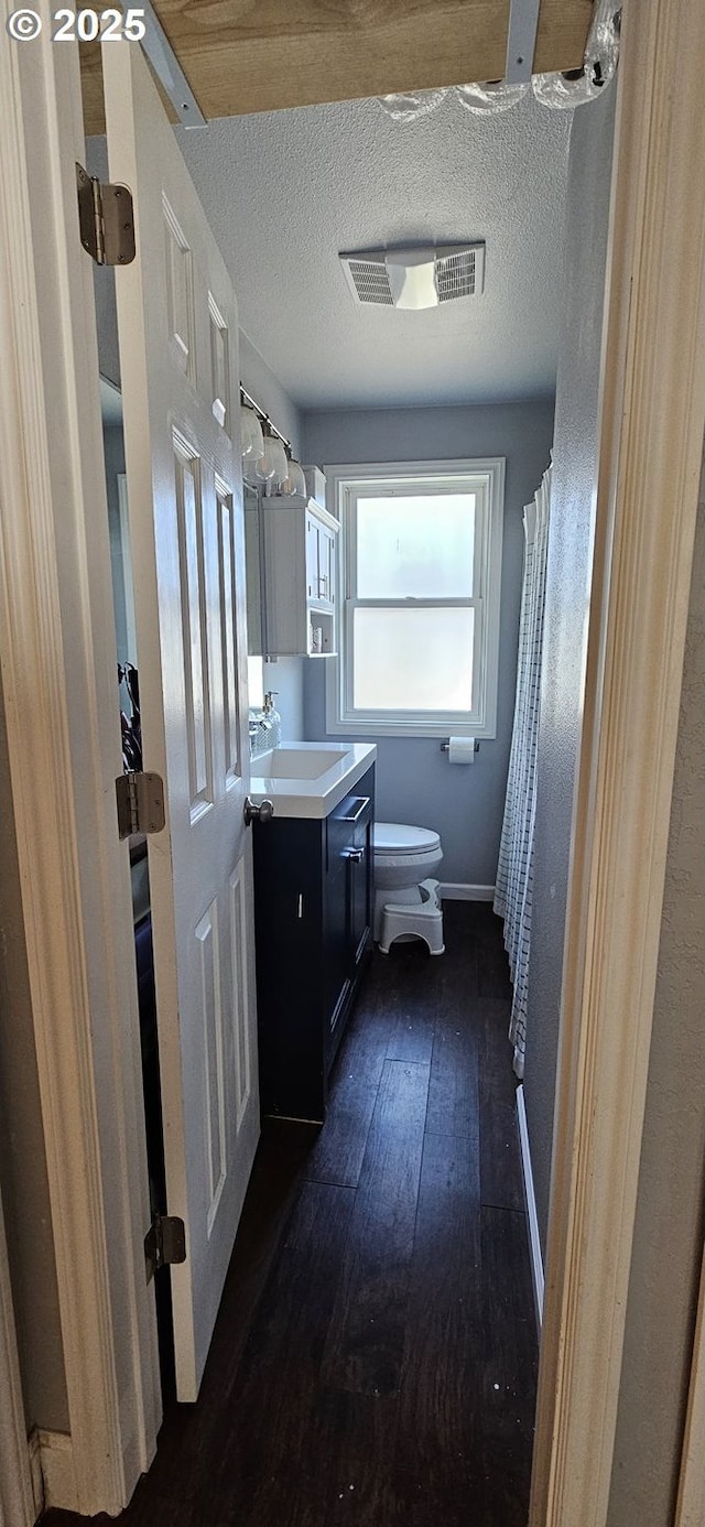 bathroom featuring a textured ceiling, toilet, vanity, and hardwood / wood-style floors