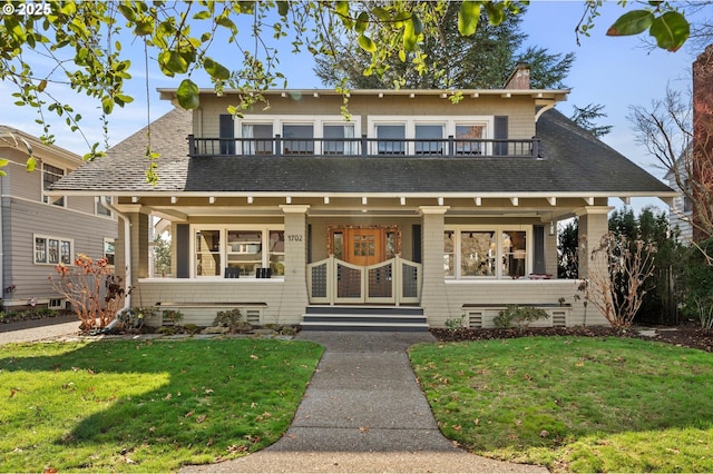 view of front of home with a front yard, a balcony, and a chimney