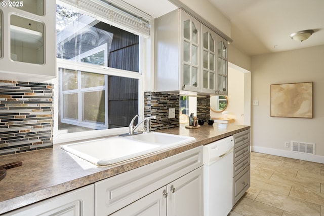 4770 SW Beech Dr, Beaverton, OR 97005 - kitchen with white dishwasher, a sink, backsplash, and glass insert cabinets
