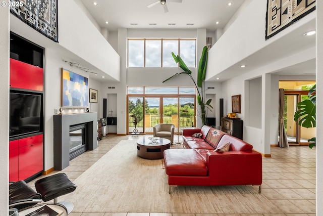 88369 Timberline Dr, Veneta, OR 97487 - tiled living area featuring a healthy amount of sunlight, a towering ceiling, a fireplace with flush hearth, and a ceiling fan