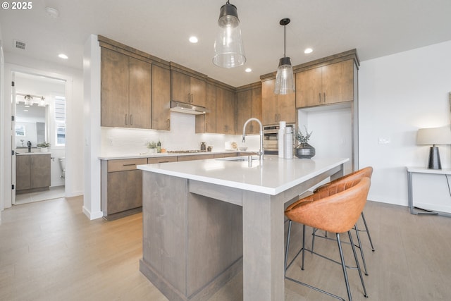 4308 N 12th Way, Ridgefield, WA 98642 - kitchen with light wood-type flooring, light countertops, brown cabinets, recessed lighting, and under cabinet range hood