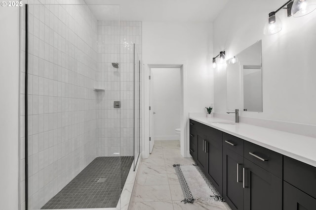 bathroom with tiled shower, vanity, and toilet