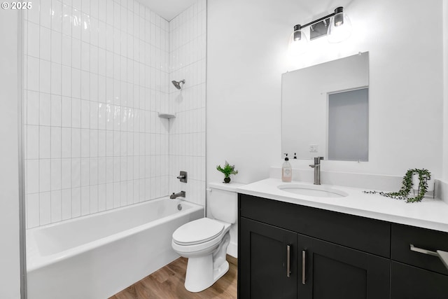 full bathroom with vanity, toilet, tiled shower / bath, and hardwood / wood-style flooring