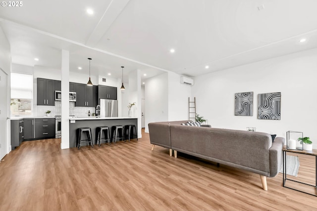 living room with light hardwood / wood-style floors and a wall unit AC