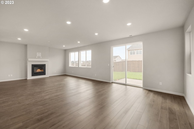 unfurnished living room featuring baseboards, dark wood-type flooring, and recessed lighting