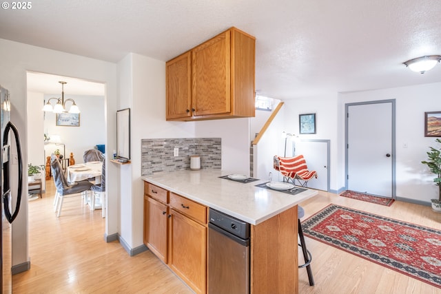 kitchen with light hardwood / wood-style flooring, kitchen peninsula, stainless steel fridge, a chandelier, and a kitchen bar