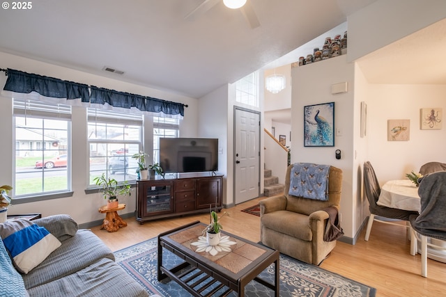 living room featuring ceiling fan, lofted ceiling, and light hardwood / wood-style flooring