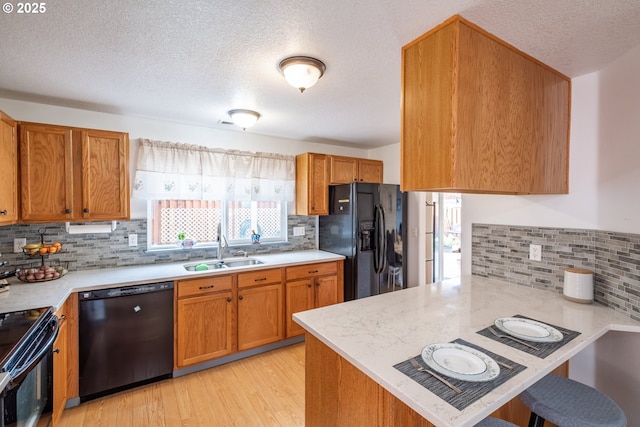 kitchen featuring kitchen peninsula, a wealth of natural light, sink, and black appliances