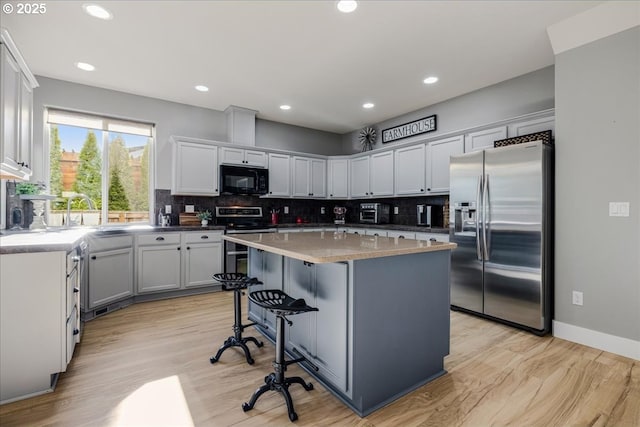 kitchen with light stone countertops, appliances with stainless steel finishes, a kitchen breakfast bar, sink, and a kitchen island