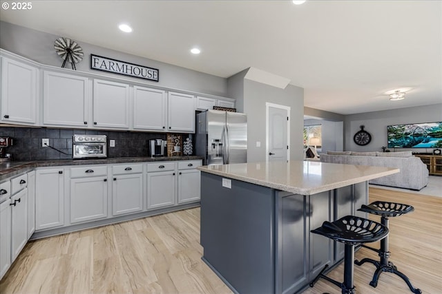 kitchen featuring a kitchen breakfast bar, white cabinets, and stainless steel fridge with ice dispenser