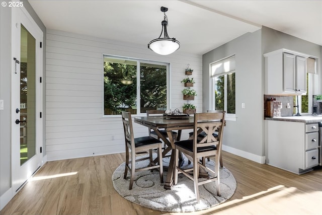 dining room featuring light hardwood / wood-style floors and wooden walls