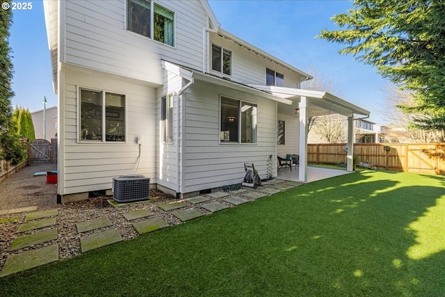 back of property with cooling unit, a patio area, and a lawn