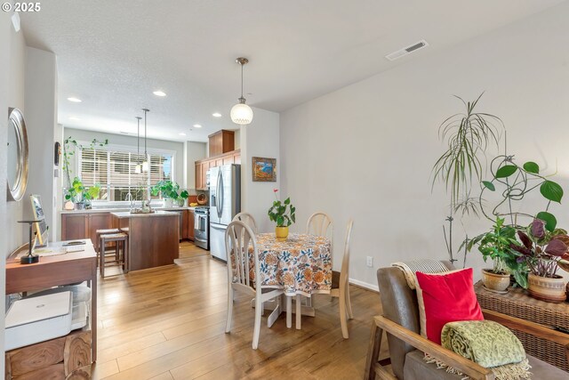 dining space with baseboards, recessed lighting, a textured ceiling, visible vents, and light wood finished floors