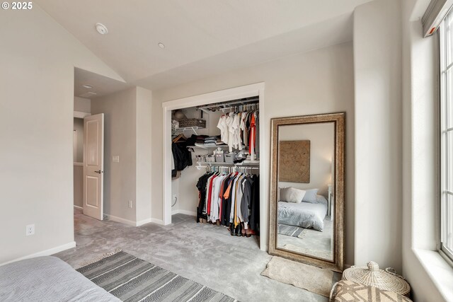 carpeted bedroom featuring a closet, baseboards, and lofted ceiling