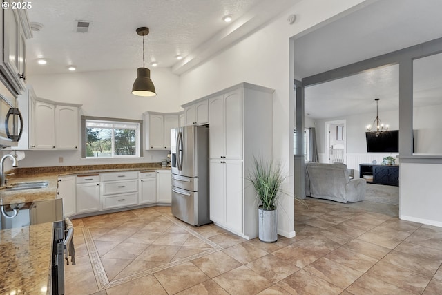 kitchen featuring light stone counters, stainless steel refrigerator with ice dispenser, visible vents, open floor plan, and a sink