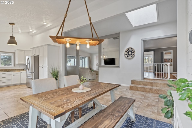 dining area featuring a textured ceiling, lofted ceiling with skylight, light tile patterned flooring, and baseboards