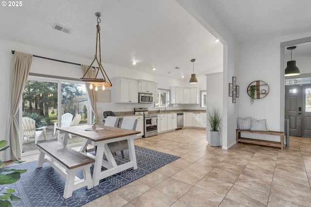 dining area with lofted ceiling, visible vents, baseboards, and light tile patterned flooring