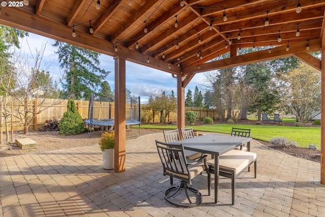 view of patio / terrace with a fenced backyard, a trampoline, and outdoor dining area