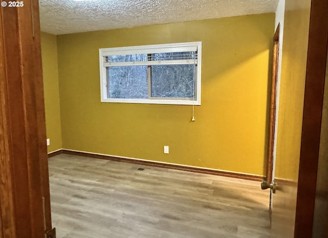 unfurnished room with wood finished floors, baseboards, and a textured ceiling