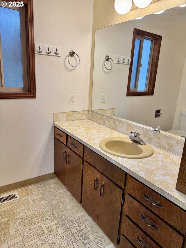 bathroom featuring visible vents, toilet, vanity, and baseboards