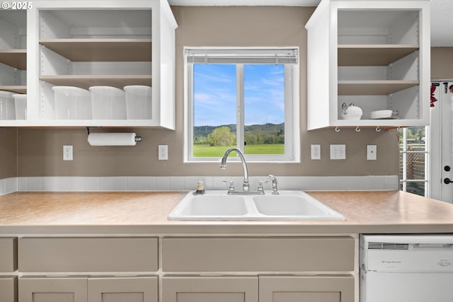 kitchen with a sink, open shelves, light countertops, and dishwasher