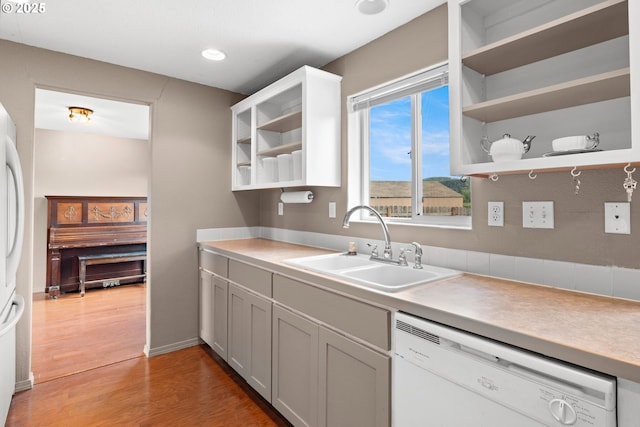 kitchen featuring white appliances, a sink, open shelves, light countertops, and light wood-type flooring