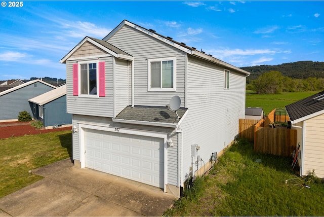 view of front of house with a mountain view, fence, an attached garage, concrete driveway, and a front lawn