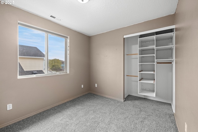unfurnished bedroom with a closet, a textured ceiling, baseboards, visible vents, and carpet floors